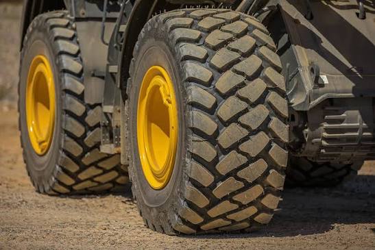 Close-up of loader tires and hydraulic bucket arm